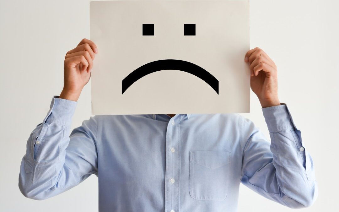 A white man holding up a frown face poster who has no work motivation.