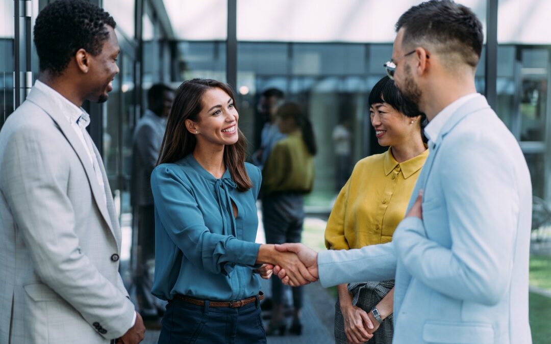 A woman shaking hand with her new employees and smiling.