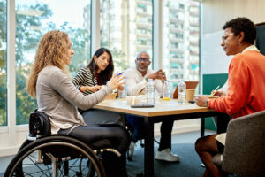 A group of diverse workers around a table meeting.